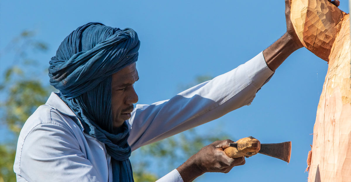 Le sculpteur Omar une herminette à la main